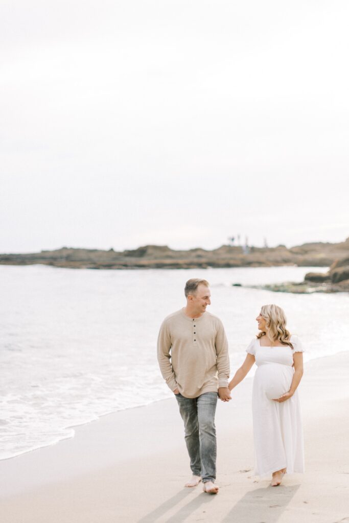 Ventura County maternity photos at the beach during golden hour, pregnant mother in flowing neutral dress at Oxnard Beach Park, coastal maternity photography inspiration in Southern California, what to wear for maternity photos in Ventura County, luxury maternity session near Ojai and Ventura beaches, romantic pregnancy photos with soft natural light, California maternity photographer capturing emotional motherhood moments outdoors